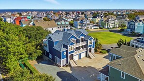 A residential area with a prominent blue house featuring a balcony and a garage. - Big Blue (North) | 1,625 ft to the beach | Dog Friendly and Community Pool (Corolla)