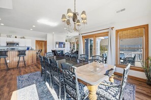 Une cuisine moderne avec des meubles blancs, un îlot central et un coin repas comprenant une grande table et des chaises.