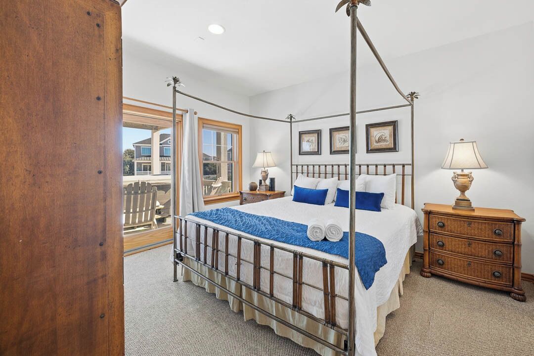 A four-poster bed with a canopy, a wooden nightstand, and a dresser.