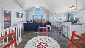 Ein geräumiger Wohnbereich mit hoher Decke, einem großen Fenster und einer Küche mit Bar.