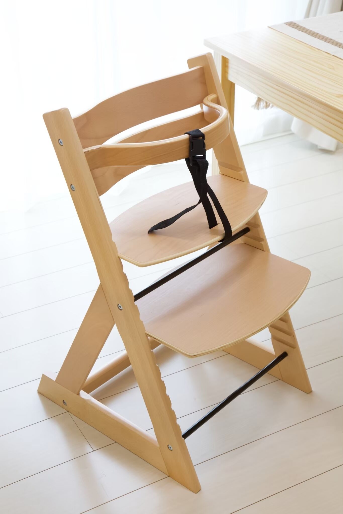 A wooden chair with a black backrest and two shelves.