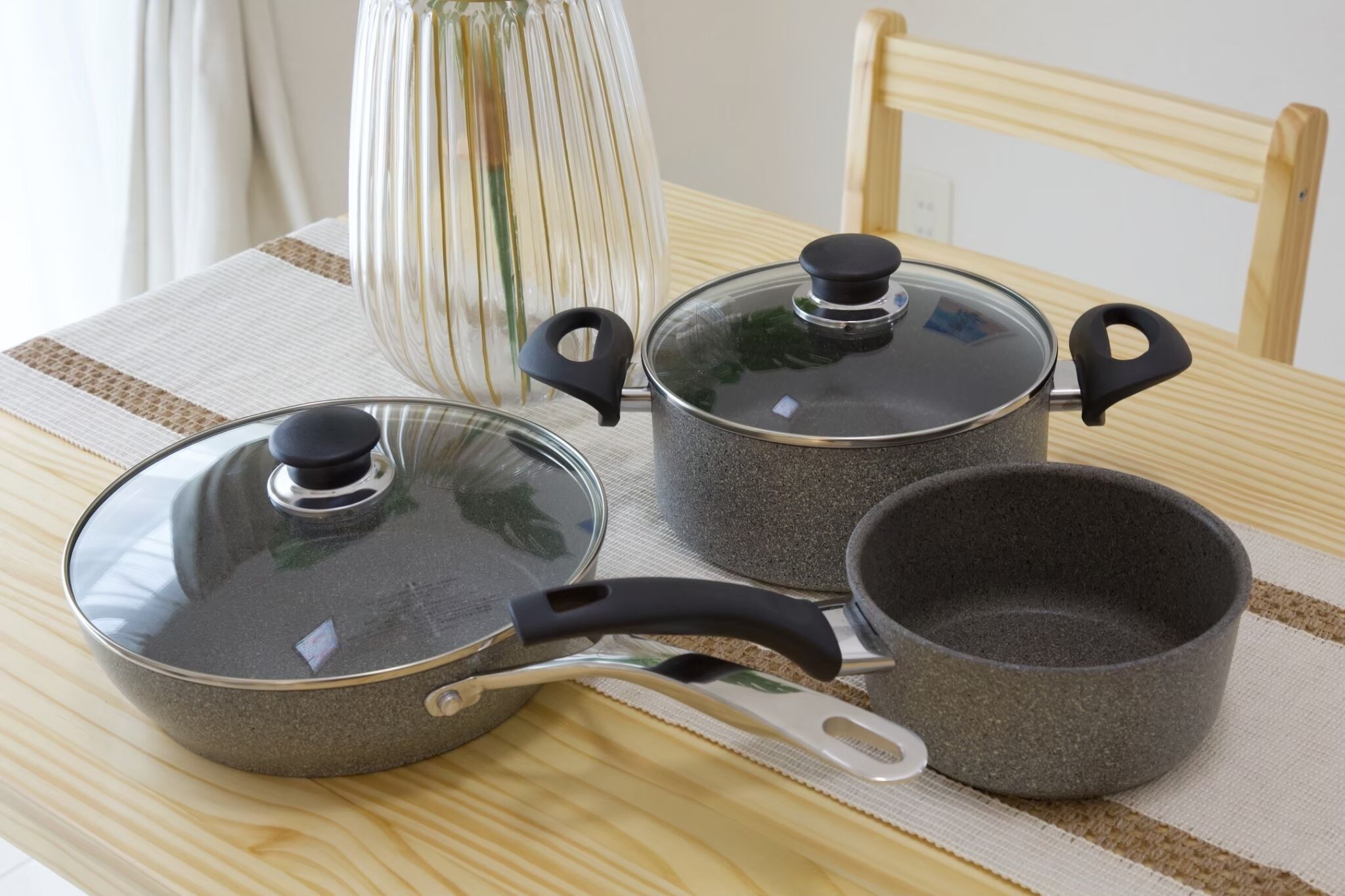 Three kitchen pots on a table with a striped tablecloth.
