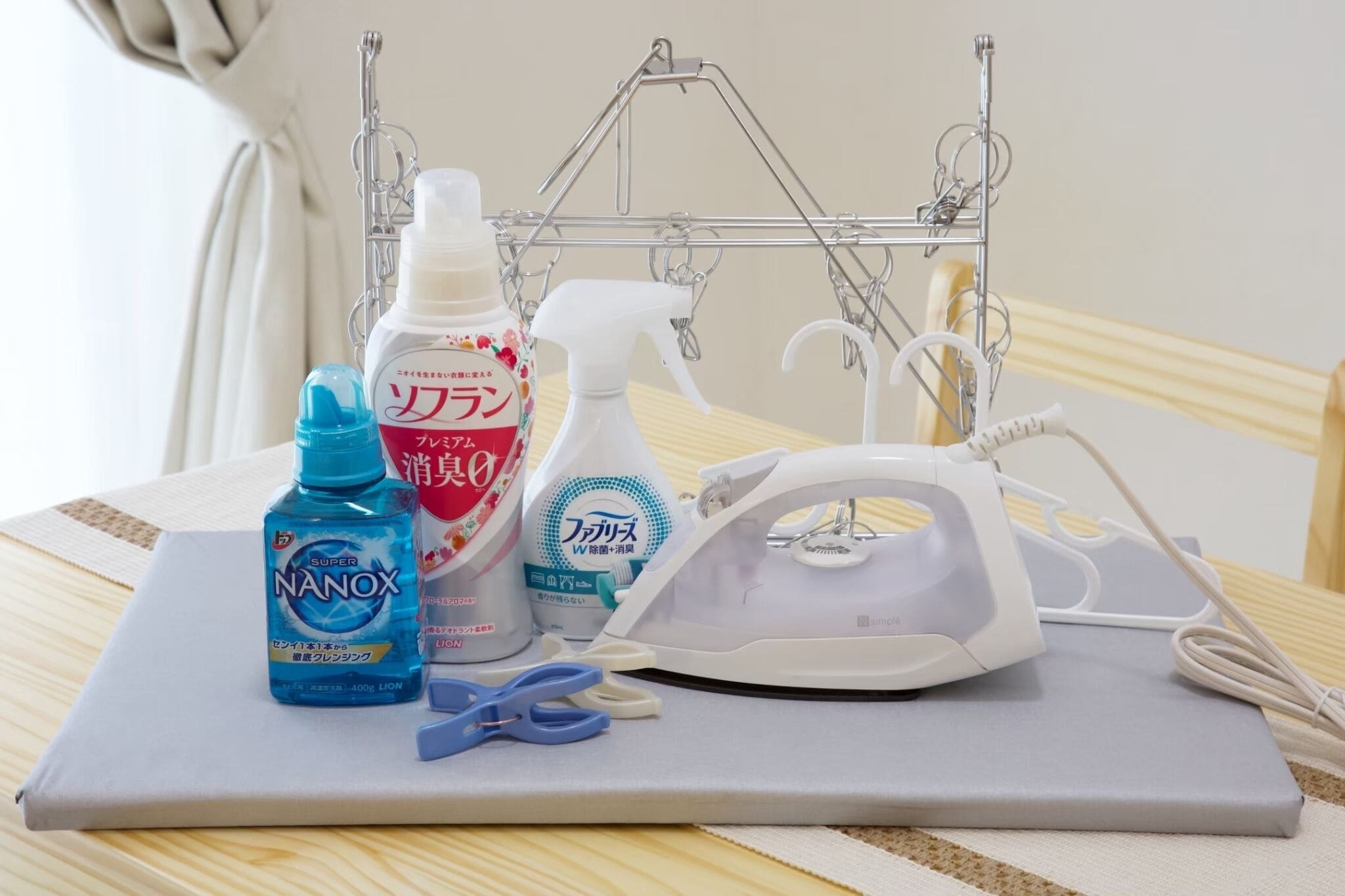 A table with cleaning supplies, a spray bottle, a bottle of liquid, a spray bottle, and a white device with a cord.