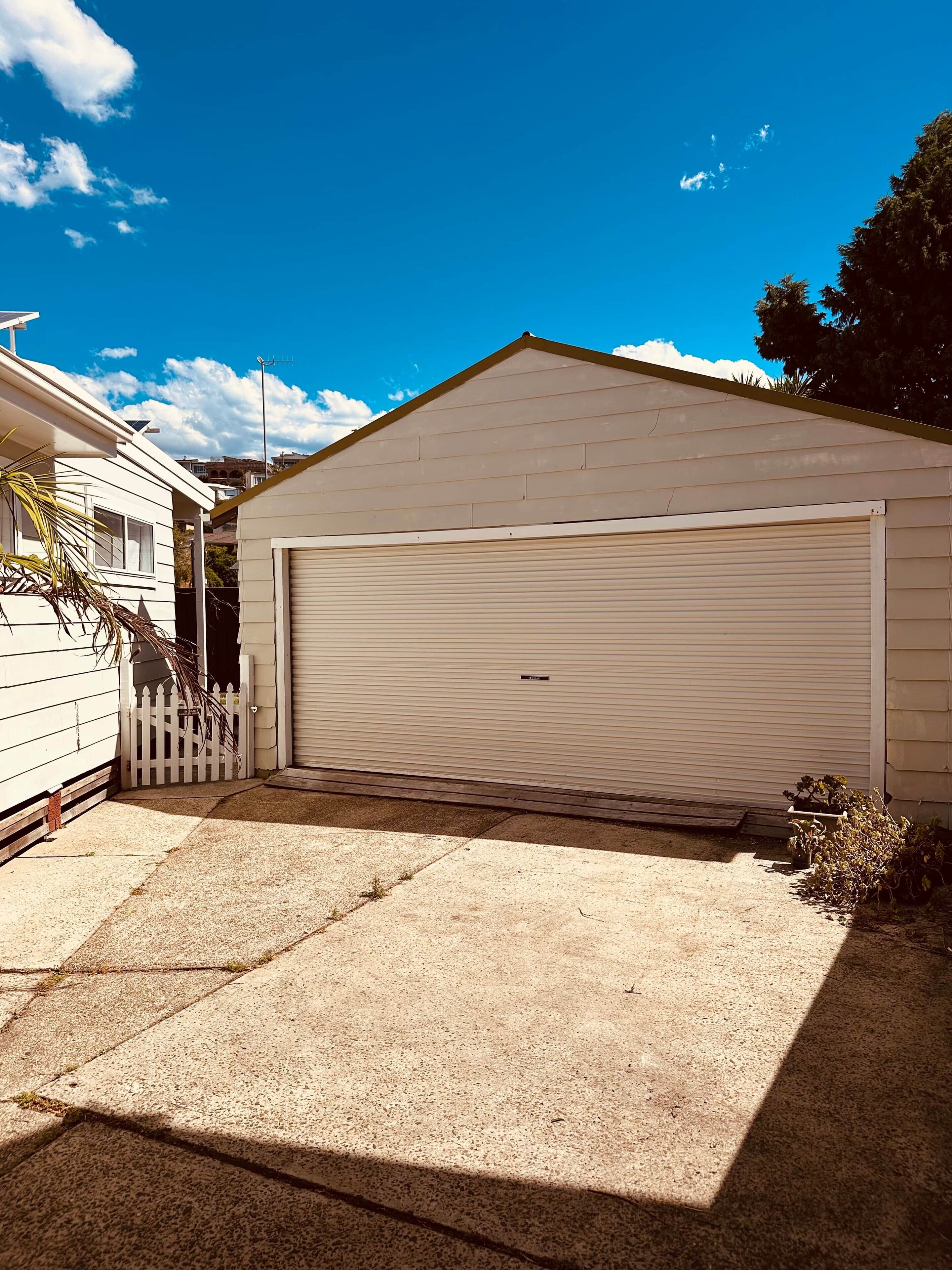 A single-story house with a garage, a white picket fence, and a small garden area.
