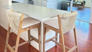A modern kitchen with a large island, two bar stools, and a view of a deck area. - Catalina's at Corlette, steps to the beach (Corlette)