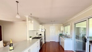 A modern kitchen with white cabinets, a grey countertop, and a wooden floor. - Catalina's at Corlette, steps to the beach (Corlette)