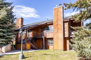 A modern multi-story building with a wooden facade, a central chimney, and a staircase leading to an upper level. - Walk to Canyons Village Charm: Vintage-Inspired Interiors, Private Patio,  Shared Pool (Park City)