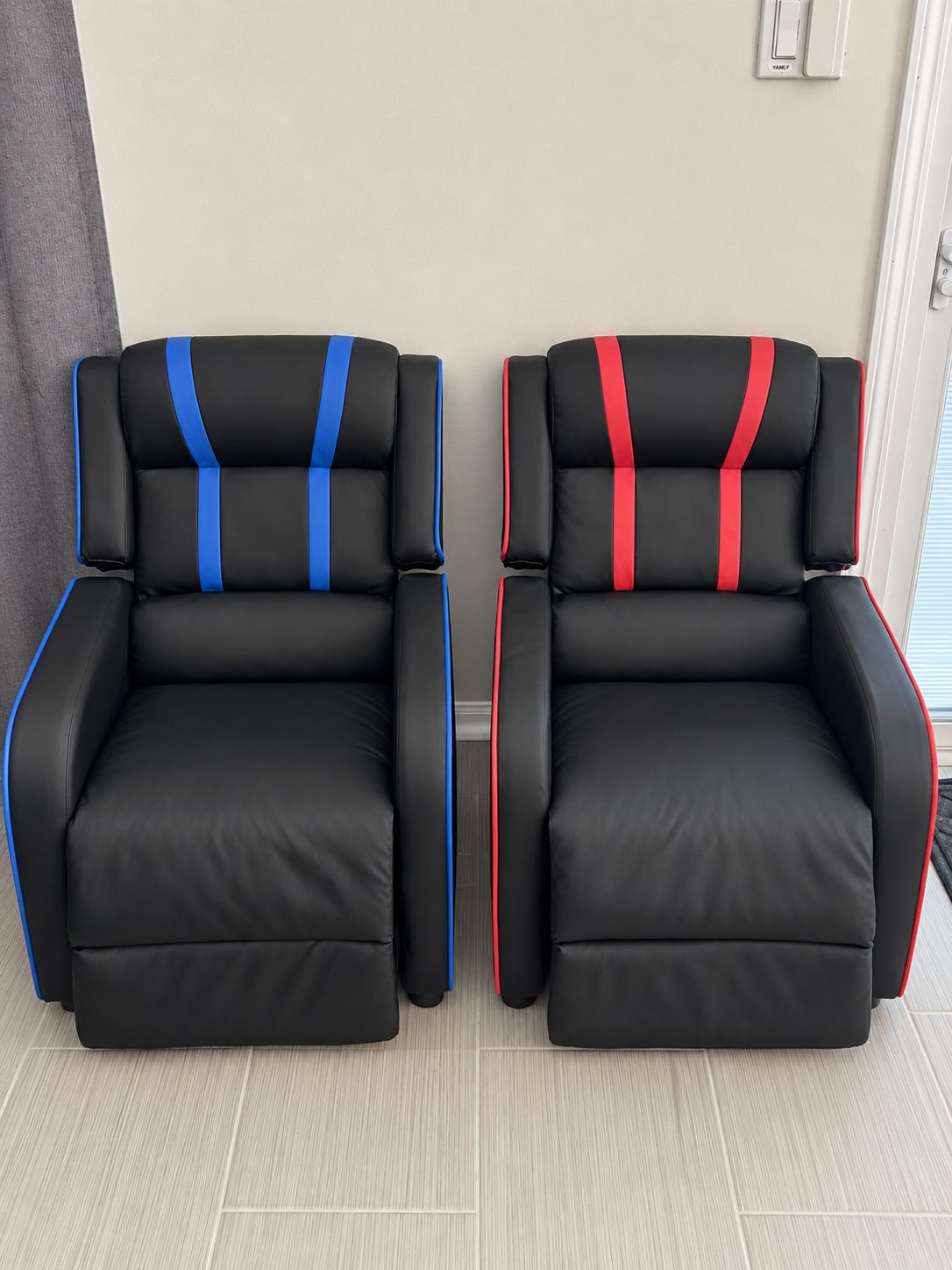 Two black chairs with blue and red stripes, positioned in a room with light-colored flooring and a door in the background.