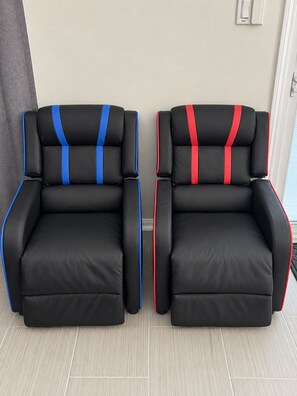 Deux chaises noires à rayures bleues et rouges, placées dans une pièce dont le sol est de couleur claire et où l’on aperçoit une porte au fond.