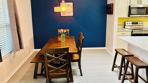 Un coin repas avec une table en bois, des chaises, un vase de fleurs et un luminaire suspendu.