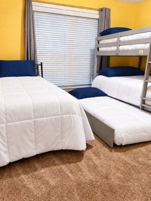Une chambre avec un lit superposé, une fenêtre, des rideaux et un sol recouvert de moquette.