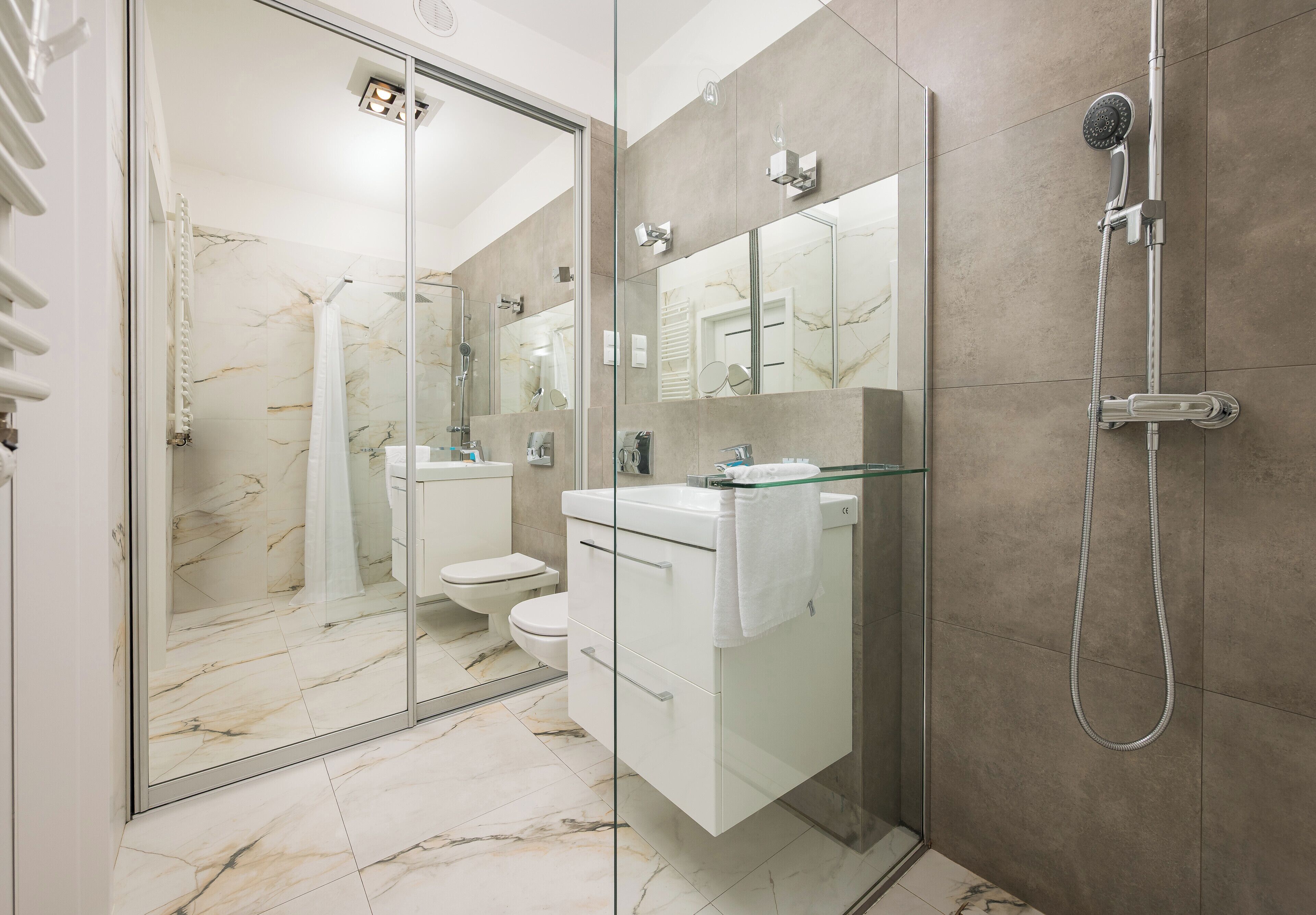 Une salle de bain moderne avec une douche à l’italienne, un lavabo blanc et un grand miroir.