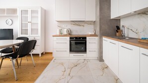 Una cucina moderna con mobili bianchi, una parete rivestita in marmo e un forno integrato.