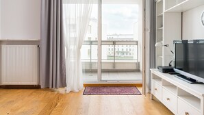 Un soggiorno moderno con una grande finestra, una televisione a schermo piatto e un mobile TV bianco.