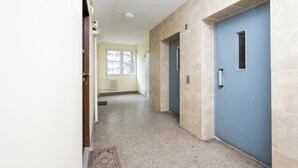 Un pasillo con una puerta azul, paredes color beige y una alfombra estampada.