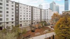 Un edificio residencial de varios pisos con un patio central, rodeado de árboles y un cielo despejado.
