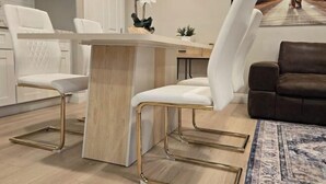 Ένα μοντέρνο σαλόνι με έναν λευκό καναπέ, έναν καφέ καναπέ και μια λευκή πολυθρόνα με χρυσά πόδια.