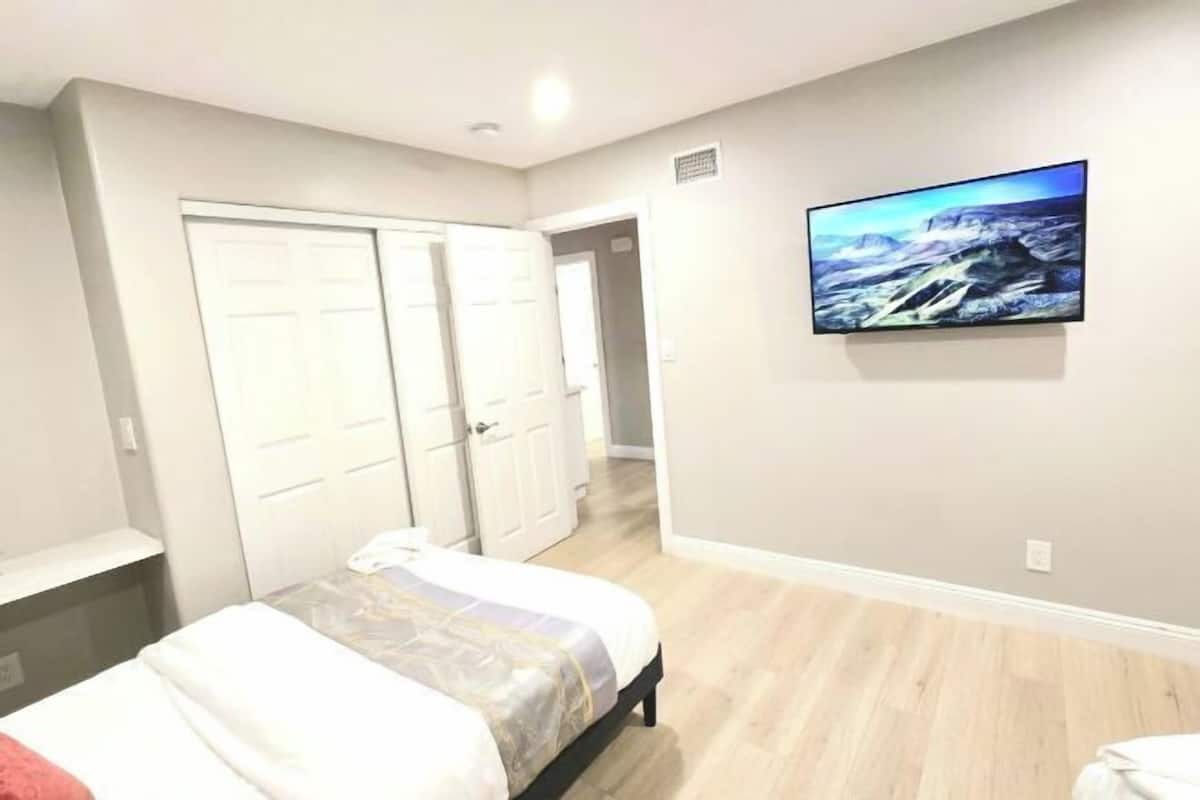 A bedroom with a bed, a TV, a wardrobe, and a hallway.