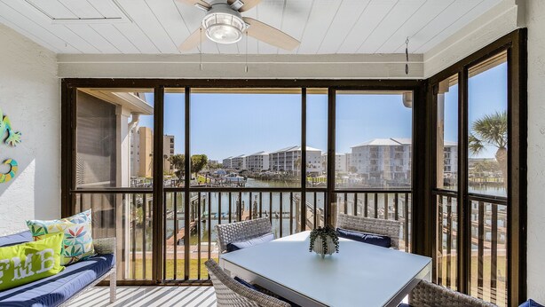 A balcony with a table and seating, overlooking a marina and buildings. - Charming Walkable 1BR condo with Canal View and Heated Pool (Fort Myers Beach)