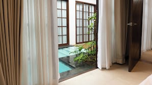A view through a doorway to a pool area with a plant, a tiled floor, and a building with large windows. - Brio De Agoho (Candelaria)