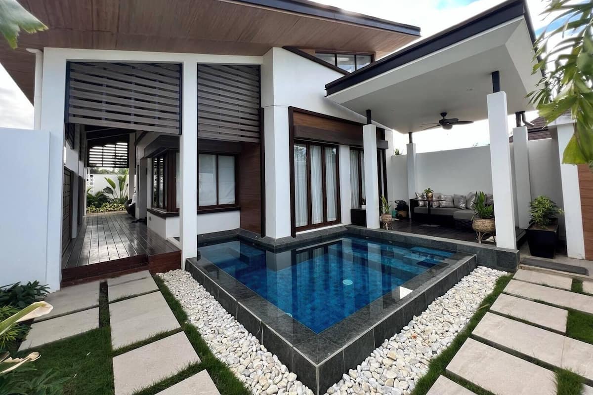 Une maison moderne dotée d’une piscine, d’un patio couvert et d’un jardin.