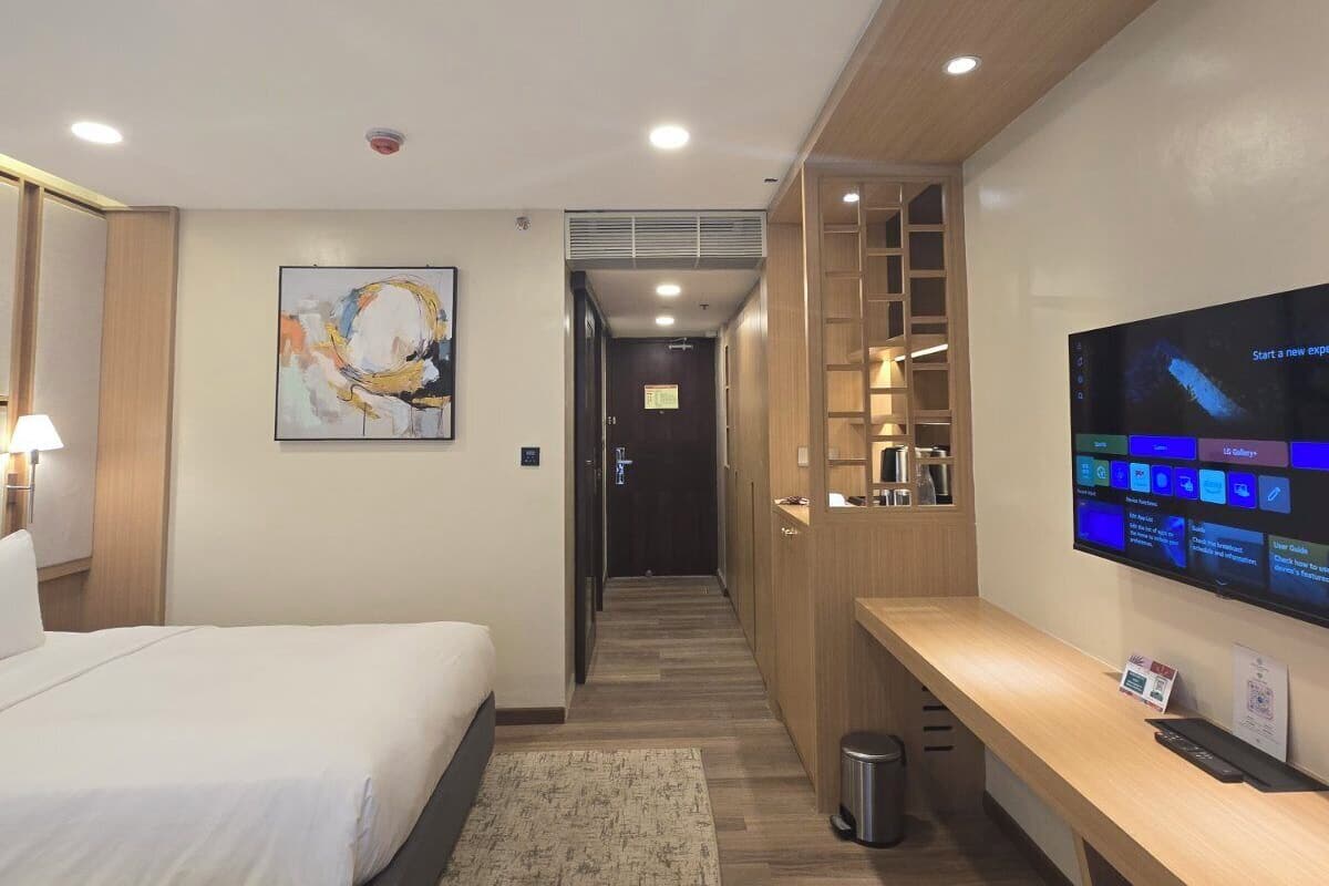 Une chambre d’hôtel comprenant un lit, un bureau, une télévision et un couloir menant à une autre pièce.
