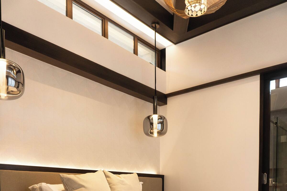 Une chambre moderne avec un grand lit, des tables de chevet, un tapis et un luminaire au plafond.