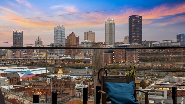 A city skyline with a view of various buildings, including a prominent UPMC building. - Modern 3BR Skyline Retreat w/ Rooftop Deck + Free Parking + Views (Pittsburgh)