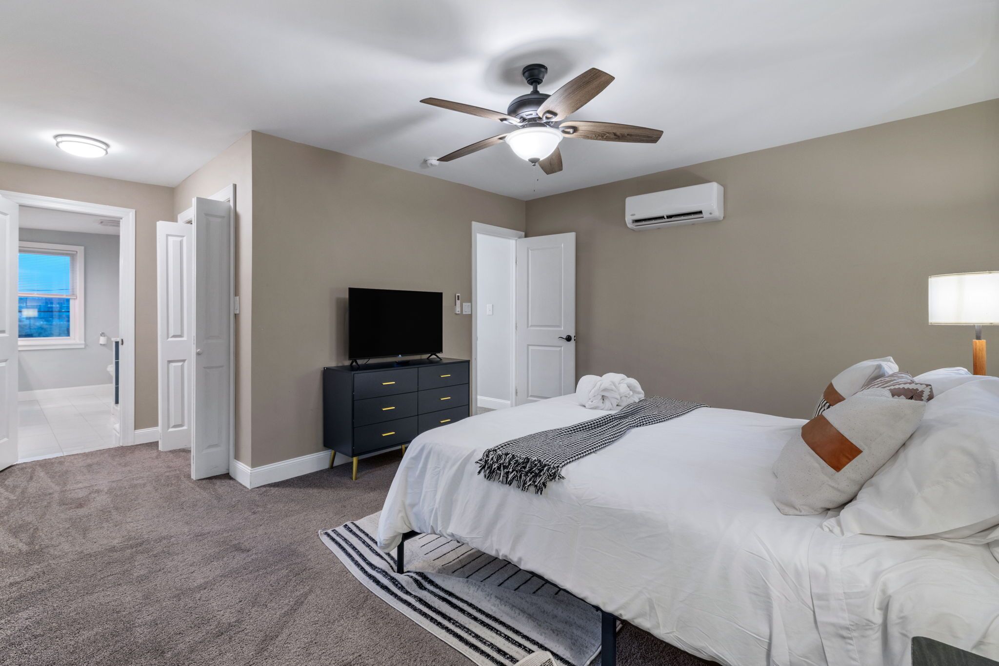 Quarto com cama, ventoinha no teto, televisão, cômoda e ar condicionado.