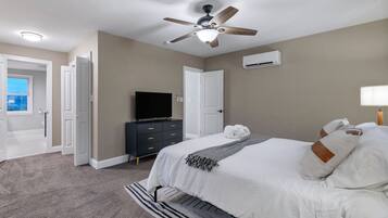 Quarto com cama, ventoinha no teto, televisão, cômoda e ar condicionado.