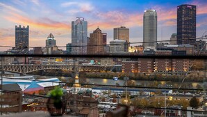 A city skyline with prominent buildings and a river. - Modern 3BR Skyline Retreat w/ Rooftop Deck + Free Parking + Views (Pittsburgh)
