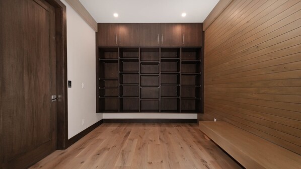 A hallway with wooden flooring, a dark wooden cabinet with multiple shelves, and a wooden wall paneling.