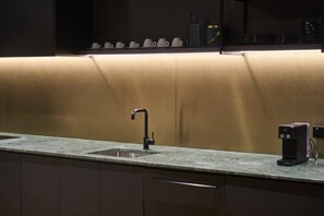 A modern kitchen with a single sink, a coffee machine, and a countertop.