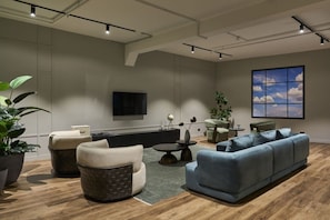 A modern living room with a sofa, armchairs, a coffee table, and a TV mounted on the wall.