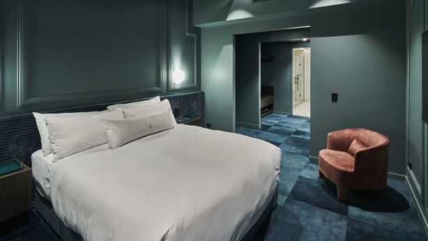Una camera d'albergo moderna con un letto grande, un comodino, una sedia e una cabina armadio.
