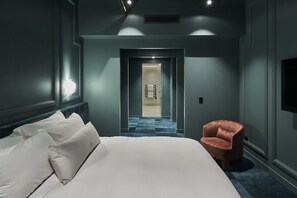 A modern hotel room with a large bed, a chair, and a TV on the wall. - The Sanctuary Suite — Quiet, Dark & Deeply Restful (Auckland)