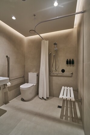A modern bathroom with a toilet, shower, and handrails. - The Sanctuary Suite — Quiet, Dark & Deeply Restful (Auckland)