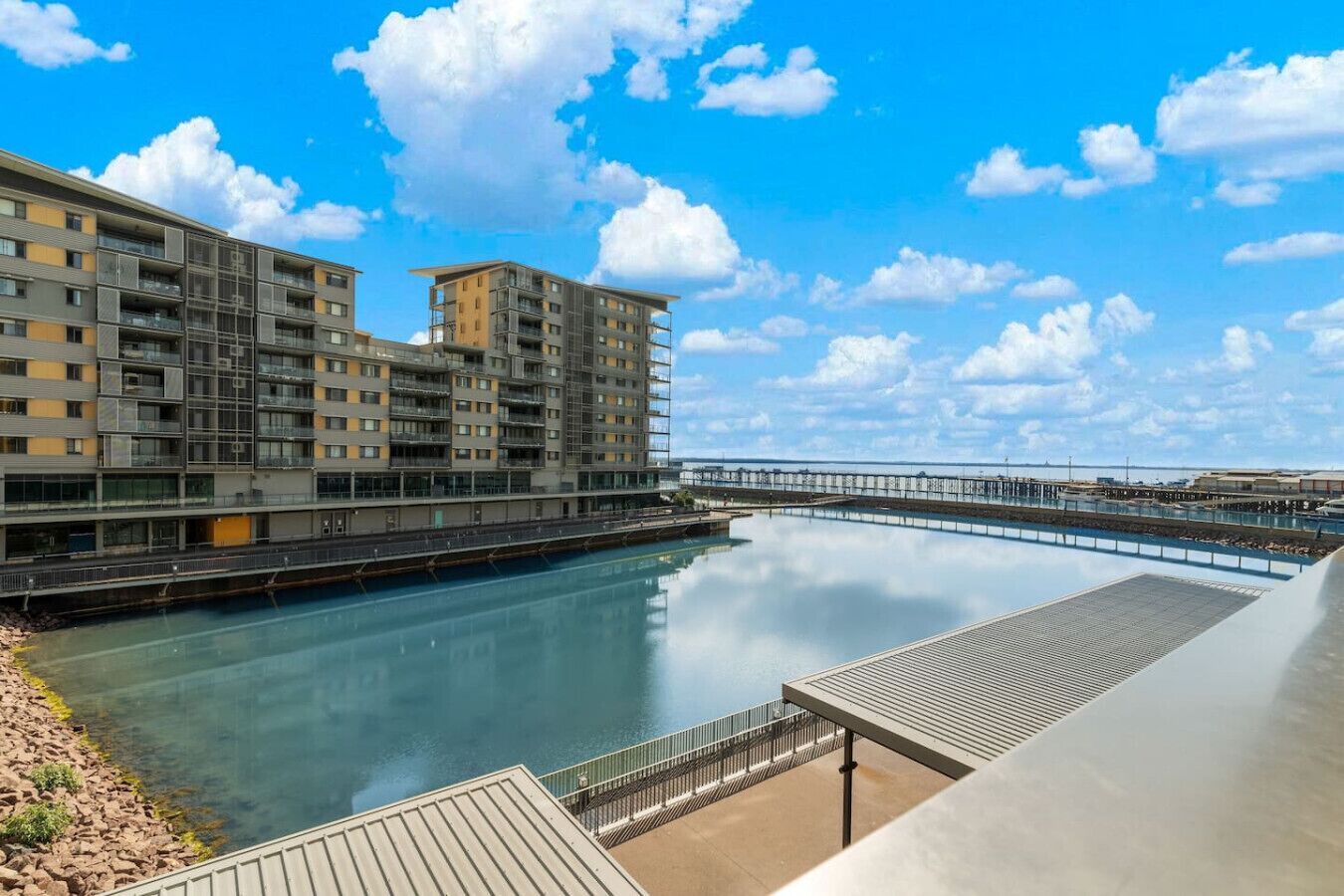 A modern building with multiple floors, a waterfront view, and a dock extending into the water.