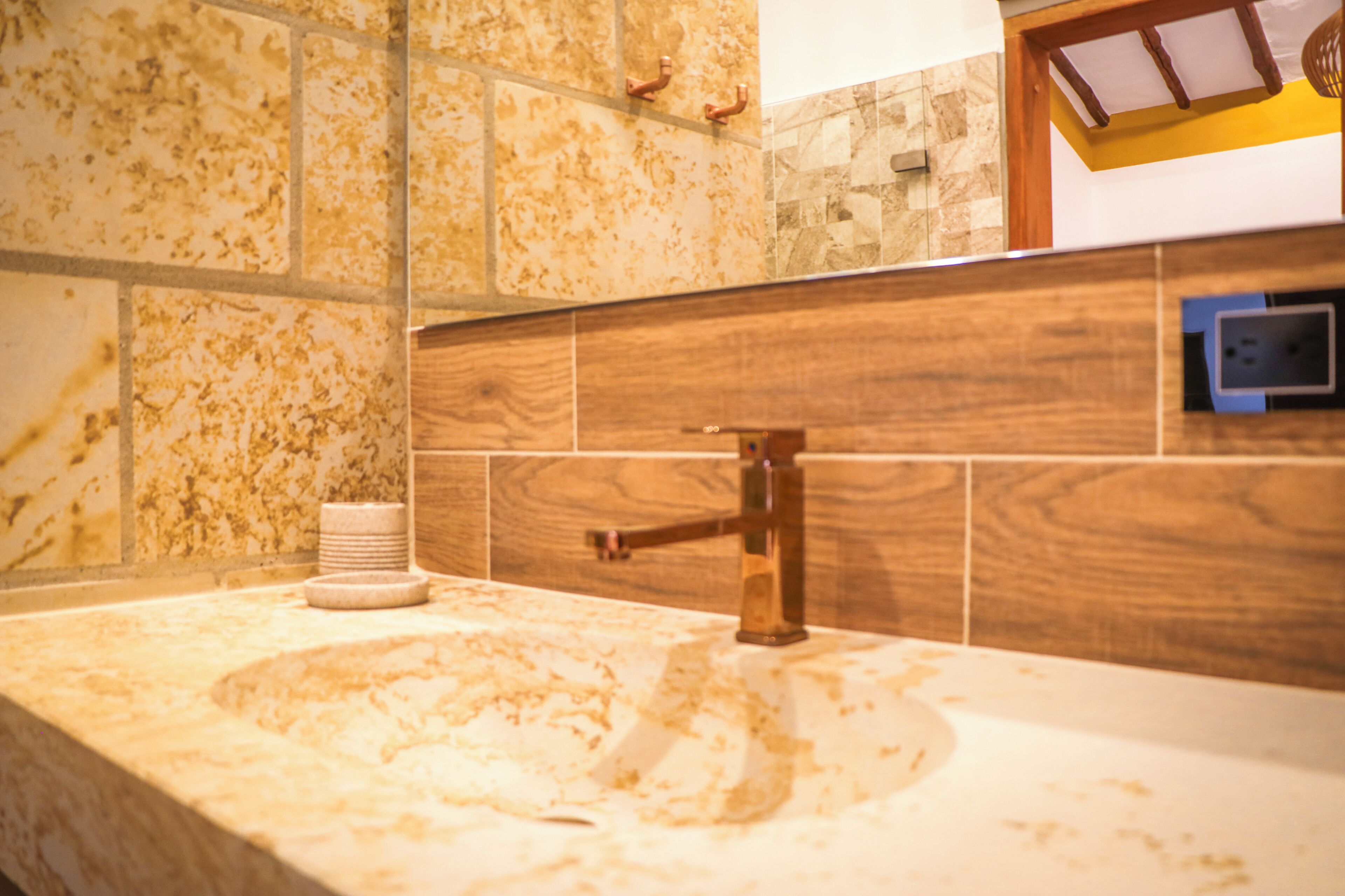 A bathroom with a marble sink, wooden wall paneling, and a visible electrical outlet.