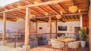 An outdoor patio with wooden pergola, wicker furniture, and potted plants. - Hotel Boutique Casa Trilo (Barichara)