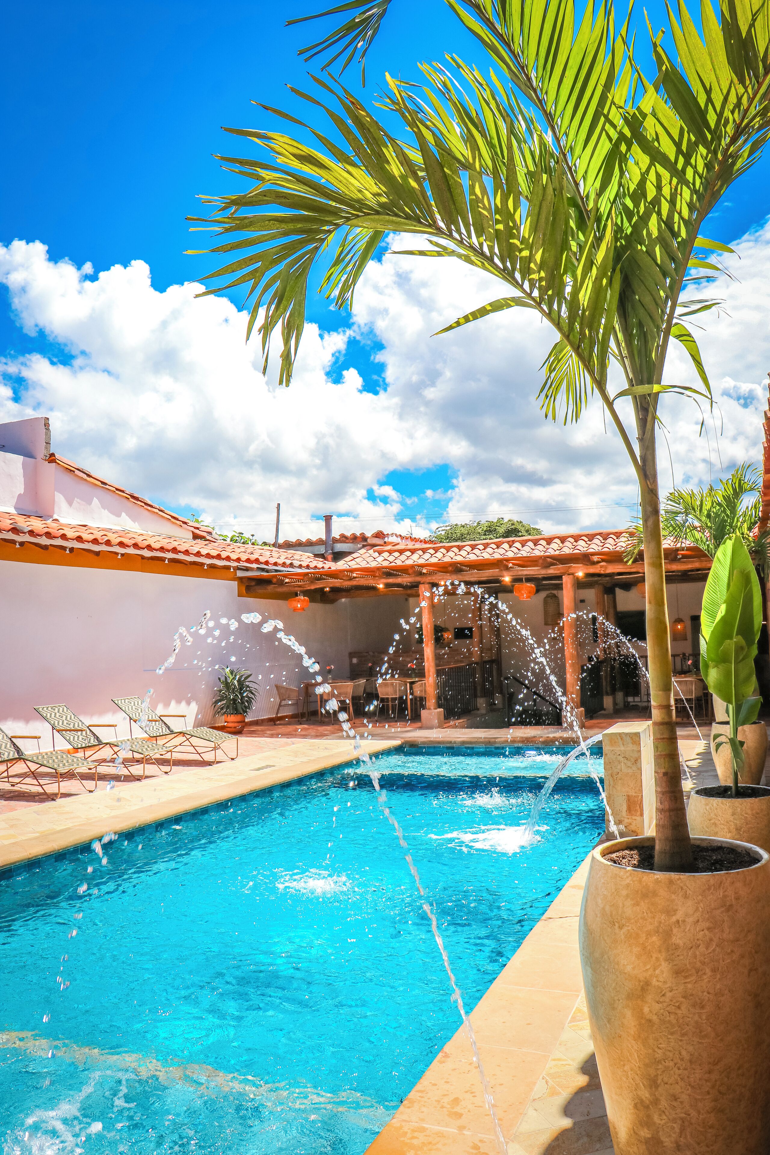A swimming pool with water jets, lounge chairs, and potted plants.