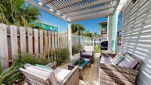 Ein überdachter Patio-Bereich mit Korbmöbeln und einem kleinen Pool.