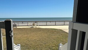A wooden deck leading to a beach view with a fence and chairs. - Mariners Watch 101 - Oceanfront Complex in Garden City Beach (Garden City)