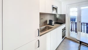 Ett modernt kök med vita skåp, en diskho i rostfritt stål och en mikrovågsugn.