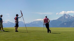 En golfbana med ett bergigt landskap i bakgrunden.
