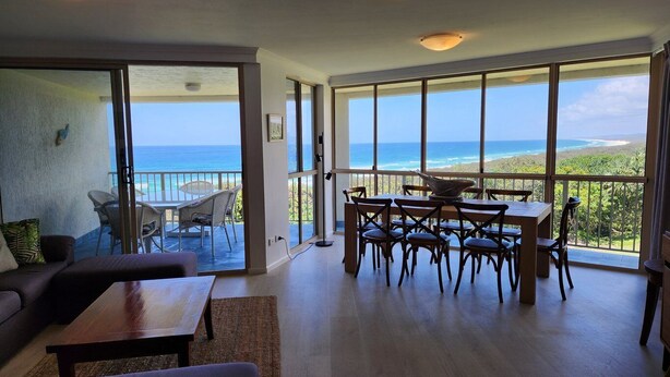 A spacious living area with a large sliding glass door leading to a balcony with a view of the ocean. - Premier Oceanfront - Large spacious 3 Bedroom in Resort (Point Lookout)