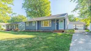 A single-story house with a front porch, a small front yard, and a garage. - Retro Style Getaway- Game room- Hot tub (South Haven)