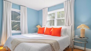 A bedroom with a bed, white curtains, a window, a lamp, and a rug. - Retro Style Getaway- Game room- Hot tub (South Haven)