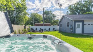 A hot tub in a backyard with a wooden fence, a shed, and a house in the background. - Retro Style Getaway- Game room- Hot tub (South Haven)