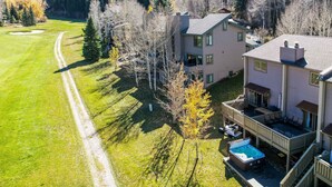 A two-story house with a deck and a hot tub, surrounded by a well-maintained lawn and trees. - EagleVail Getaway | Ski, Golf & Hot Tub (Avon)